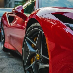 Close-up of a luxurious red sports car parked in a bustling city street.