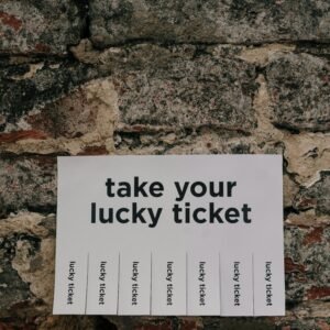 Close-up of a vintage wall with a 'take your lucky ticket' paper sign taped on, offering a whimsical message.