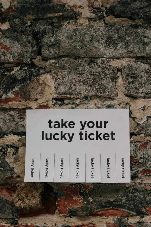 Close-up of a vintage wall with a 'take your lucky ticket' paper sign taped on, offering a whimsical message.